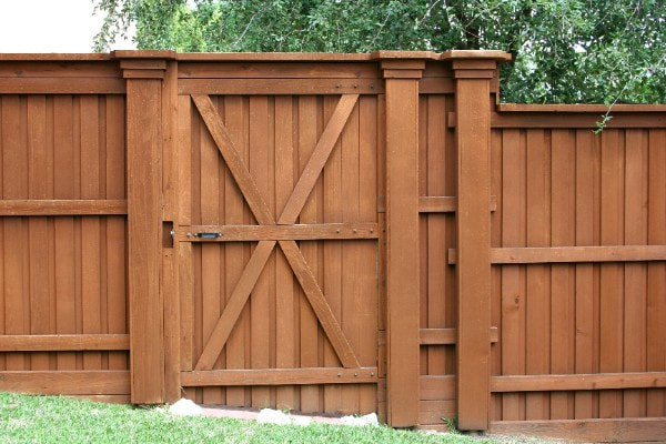 Medium brown gate and section of a stained pressure treated fence in Grange Hill East, Guelph, Ontario